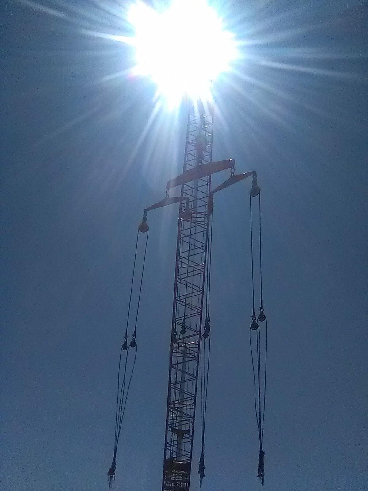 A tall tower with wires hanging from it's sides.